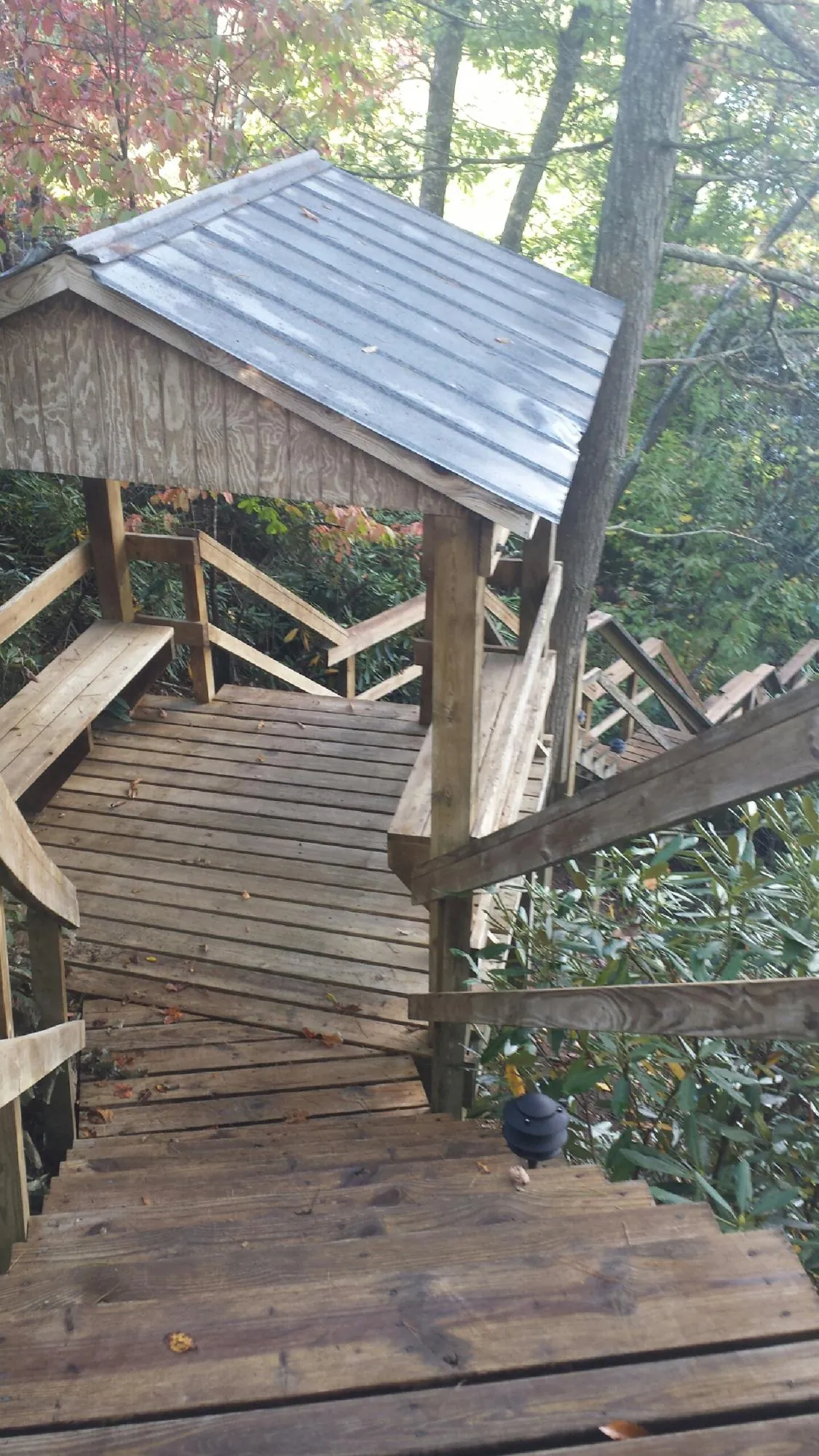 Metal roofed shelter over wooden steps on a wooded walkway — Skylight Repair & Installation work by our crew in Greensboro